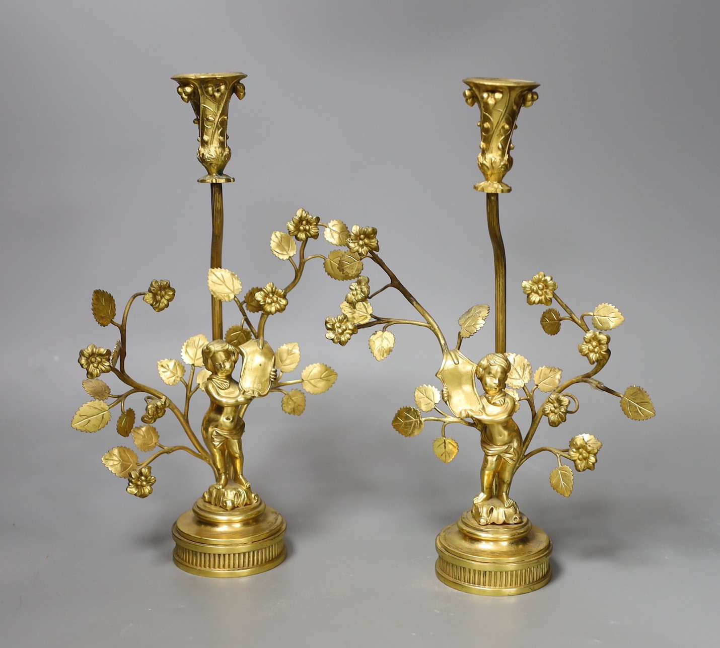 A pair of figural gilt metal candlesticks (Birmingham 1902 by Elkington & Company and Chester 1922(?) by Haseler Brothers, 28cm